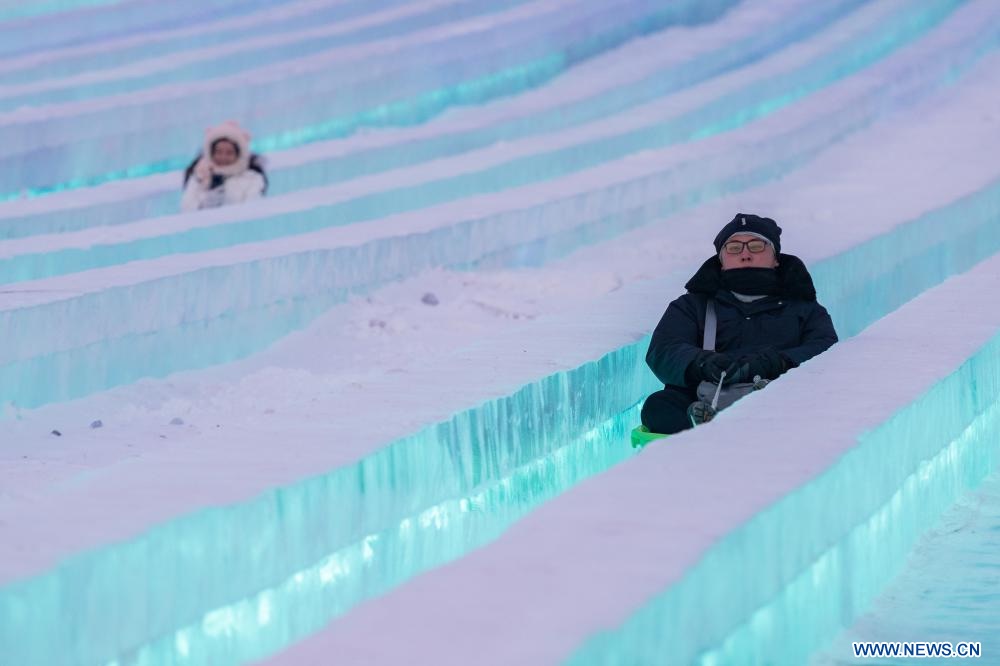 turistas disfrutando de paseos en un tobogán de hielo en el Mundo de Hielo y Nieve.