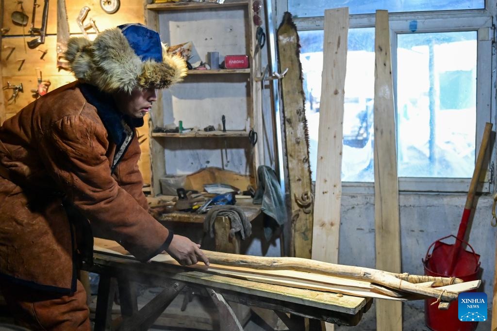 Un artesano procesa tablas de madera antes de hacer esquí de piel en una tienda tradicional de esquí de piel.